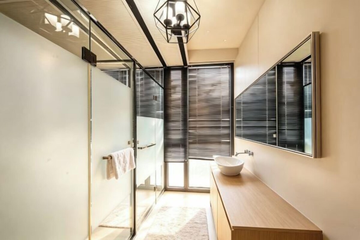 Une salle de bain moderne avec une douche à parois de verre, un grand miroir et un meuble-lavabo en bois.