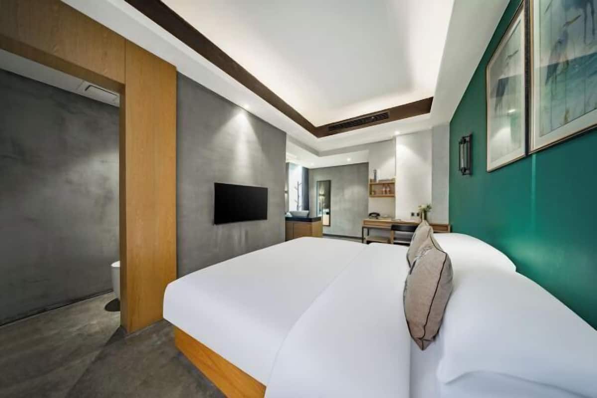 Una habitación de hotel moderna con una cama grande, un televisor de pantalla plana, una pared decorativa de madera y una pared decorativa verde.