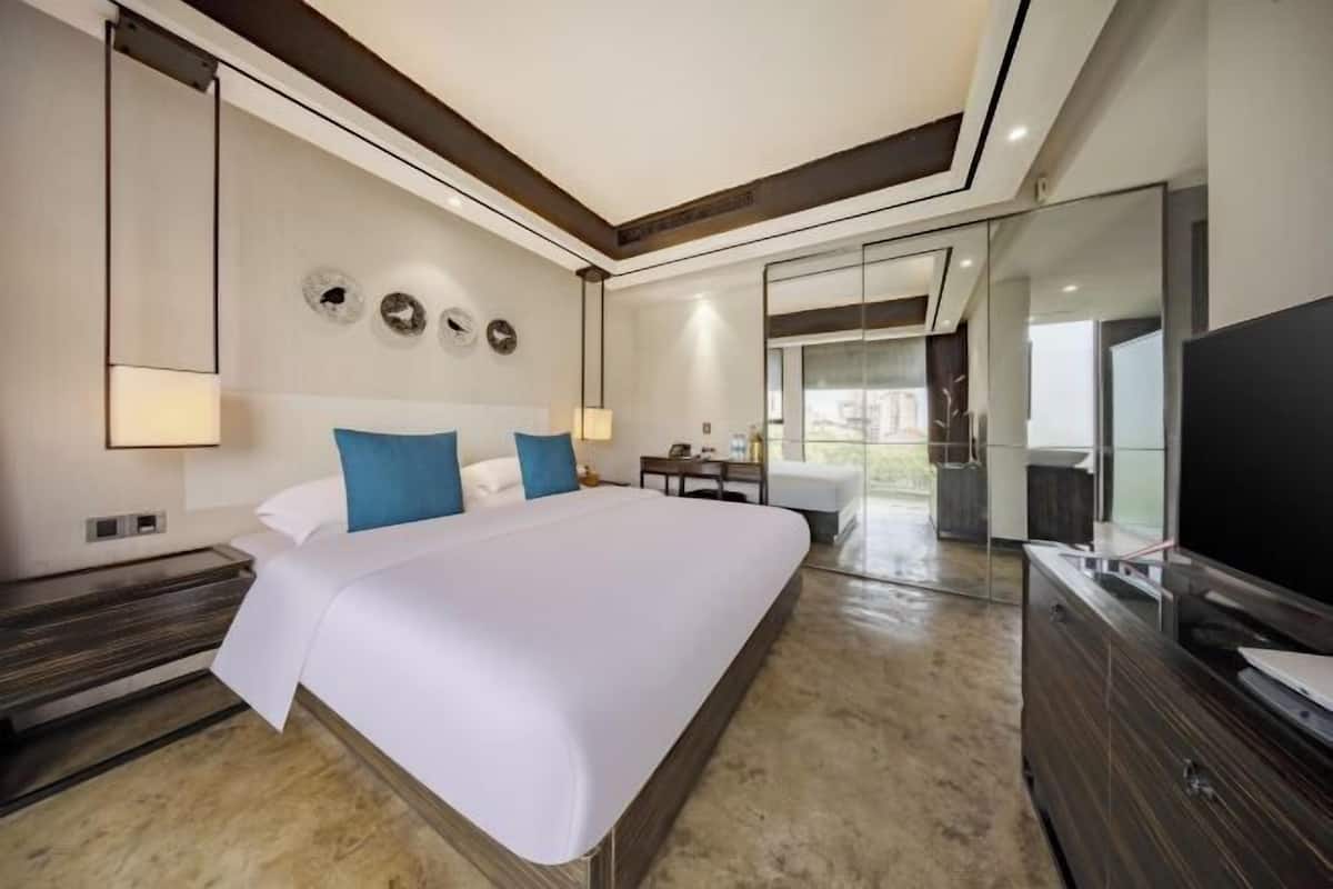 Una habitación de hotel moderna con una cama grande, un televisor de pantalla plana, un escritorio y un ventanal amplio.