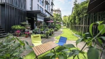 A courtyard with a seating area, potted plants, and a building facade.