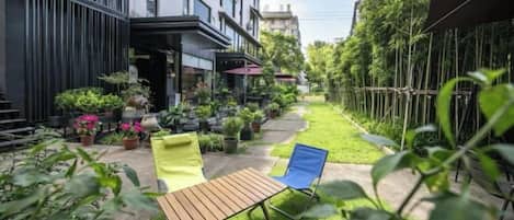 Une cour avec un espace aménagé pour s’asseoir, des plantes en pot et la façade d’un bâtiment.
