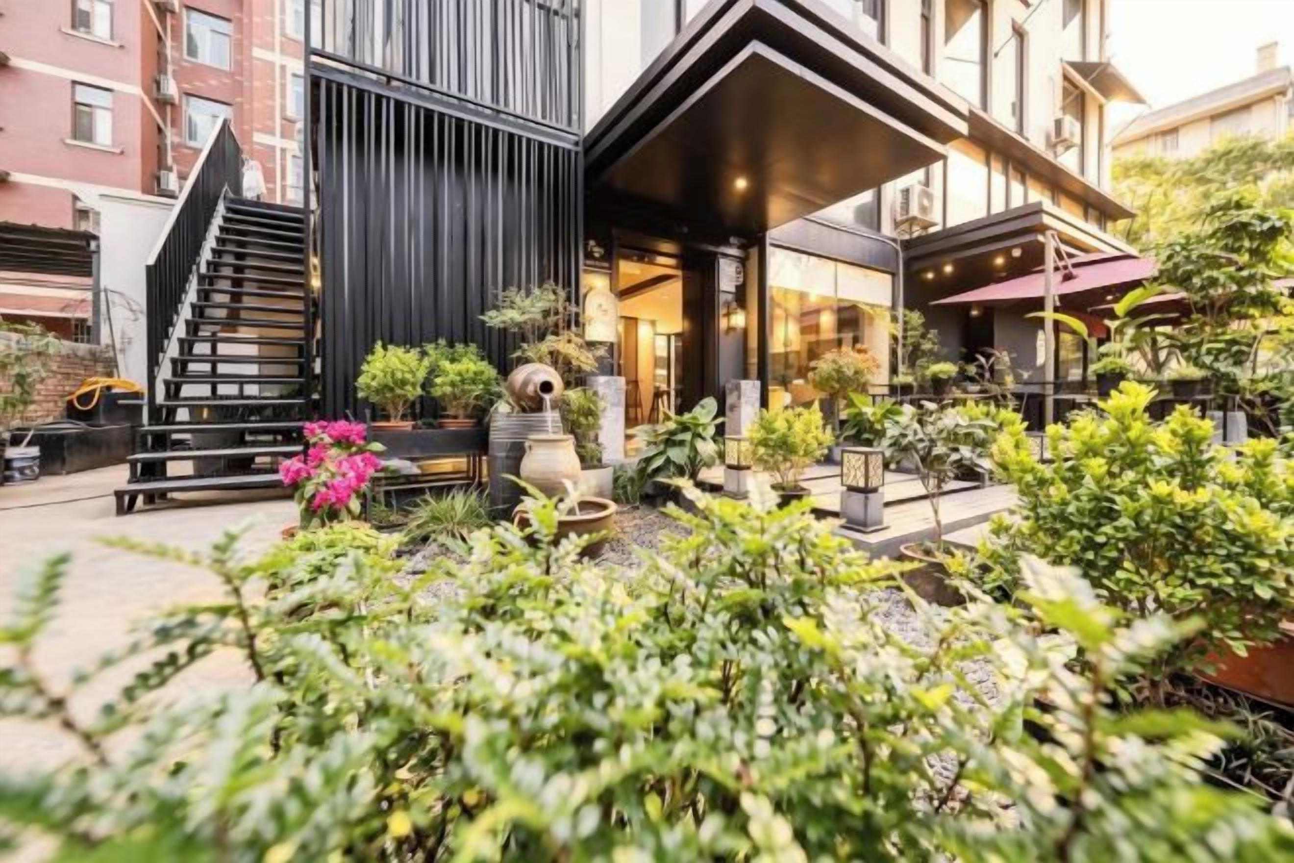 A modern building with a staircase, outdoor seating, and potted plants.
