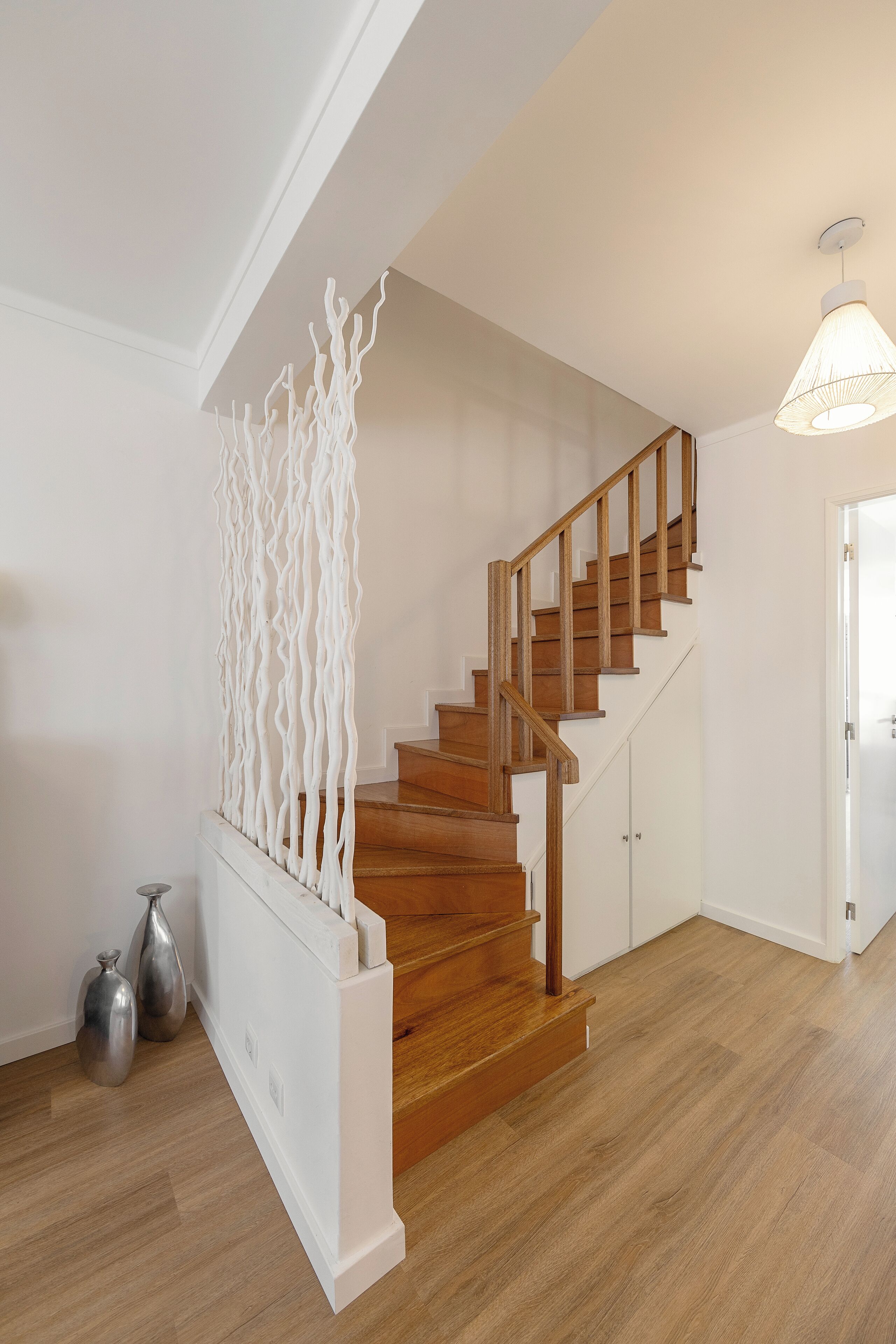 Una escalera de madera con barandilla blanca, que conduce a una puerta.