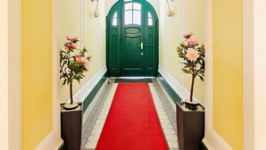 A hallway with a red carpet, green door, and potted plants. - Art Living Vienna (Vienna)