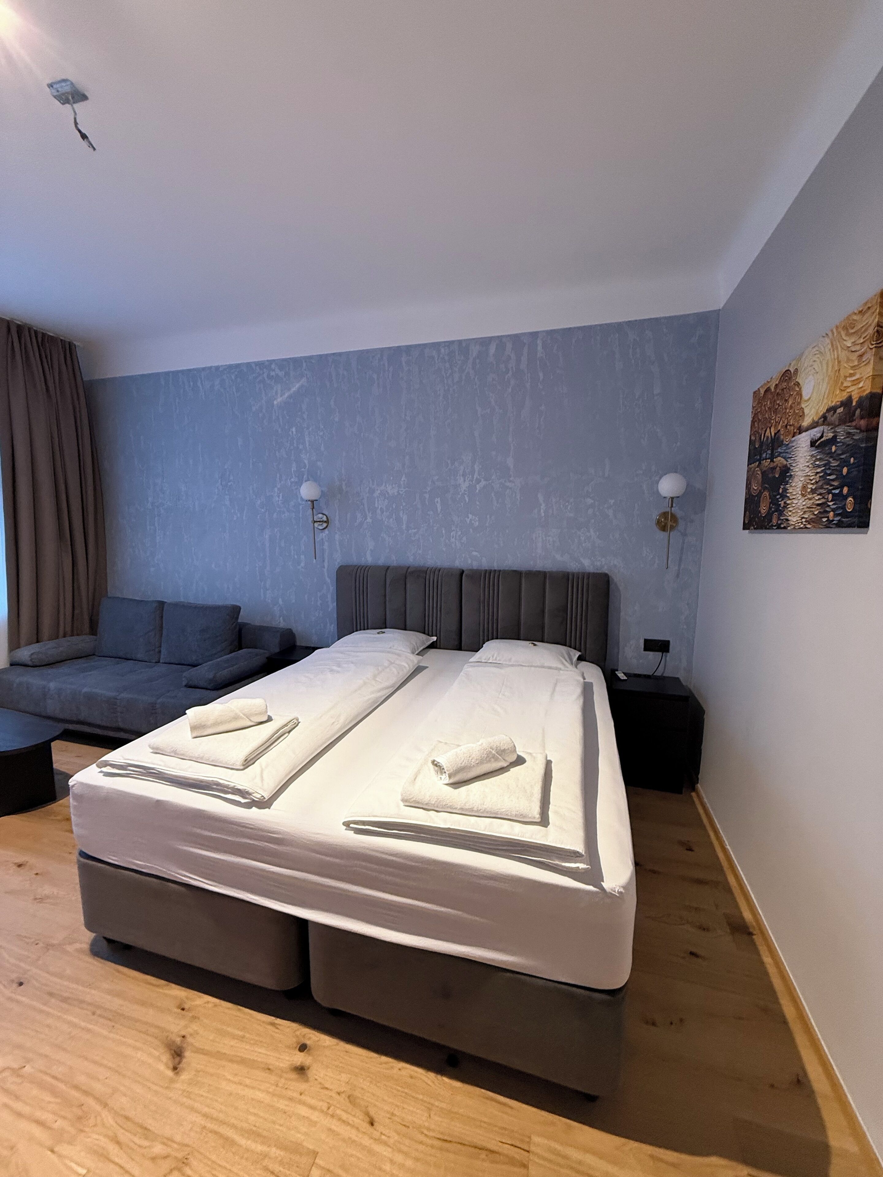 Une chambre moderne avec un grand lit, un canapé et un tableau au mur.