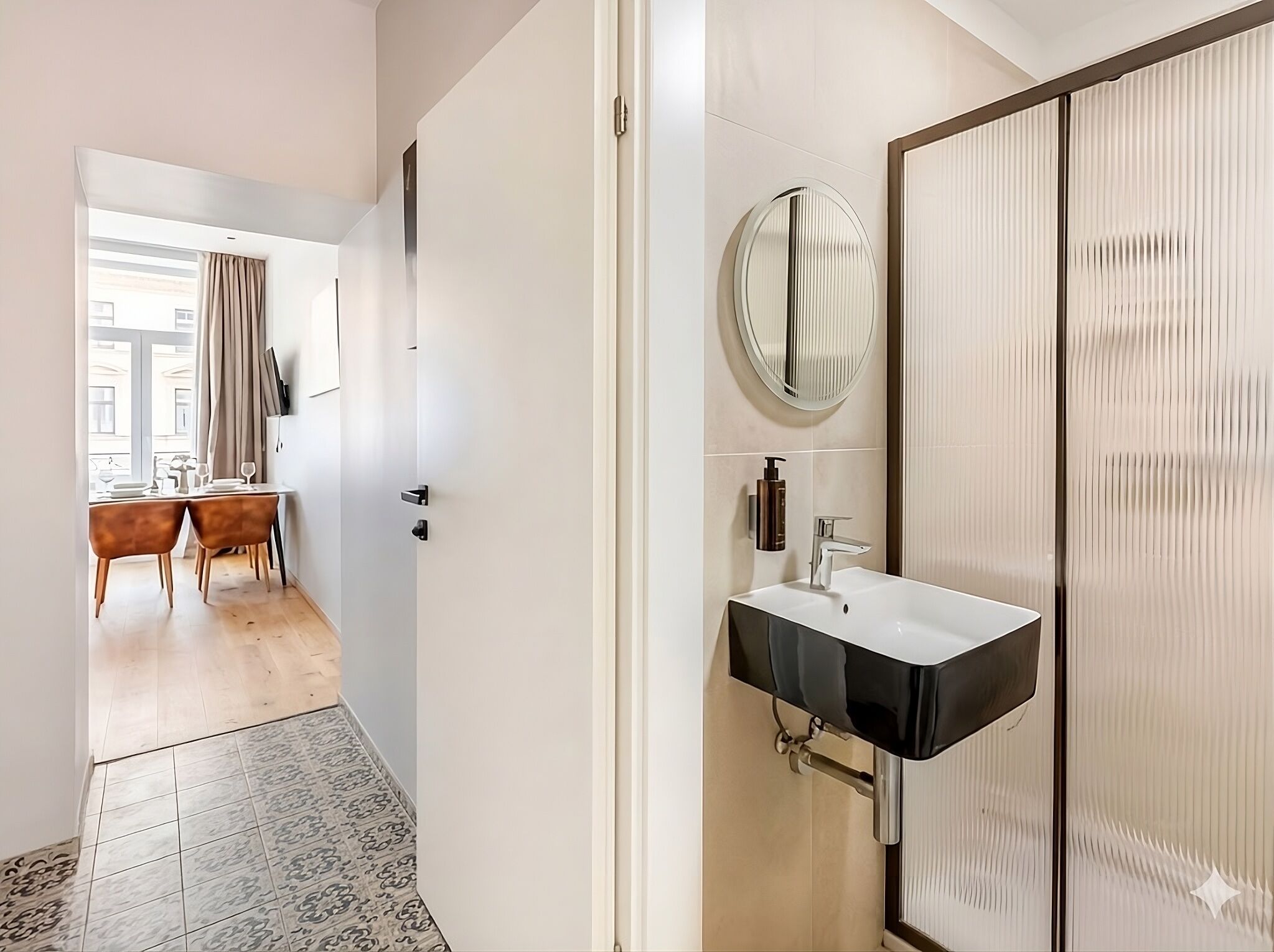 A modern bathroom with a black sink, a round mirror, and a toilet with a vertical panel design.