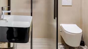 A bathroom with a glass-enclosed shower, a white sink, and a toilet.
