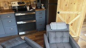 Una cocina moderna con electrodomésticos de acero inoxidable, sofás grises y una puerta de madera.