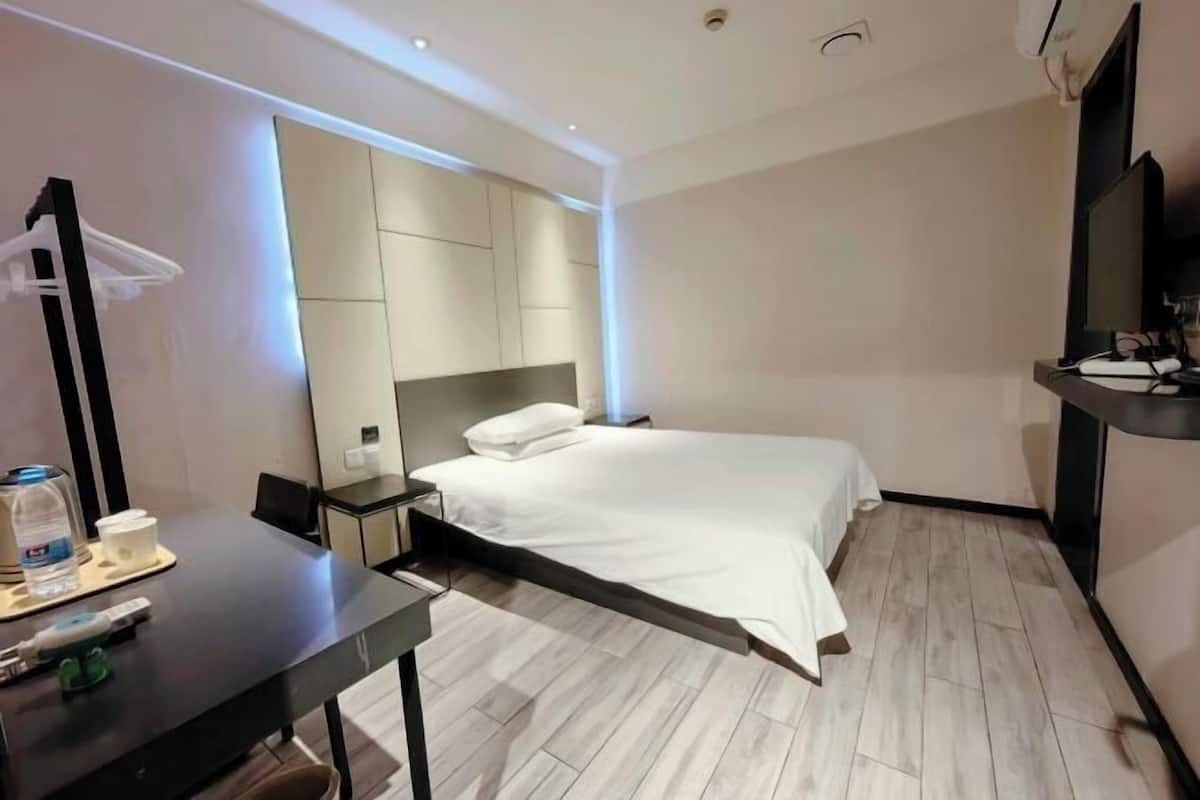Una habitación de hotel moderna con una cama, una mesita de noche y un escritorio con una silla.