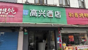 A hotel facade with a green and red sign, a closed blue shutter, and a visible room number 128. - UMYouXuan Gaoxing Hotel (Shanghai Lianhua South Road) (Shanghai)