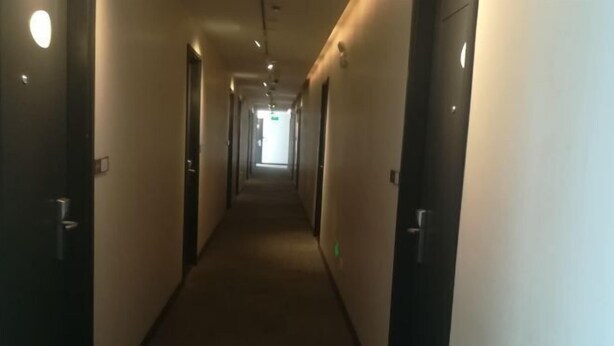 A long, narrow hallway with doors on both sides, leading to a bright exit at the end. - UMYouXuan Gaoxing Hotel (Shanghai Lianhua South Road) (Shanghai)