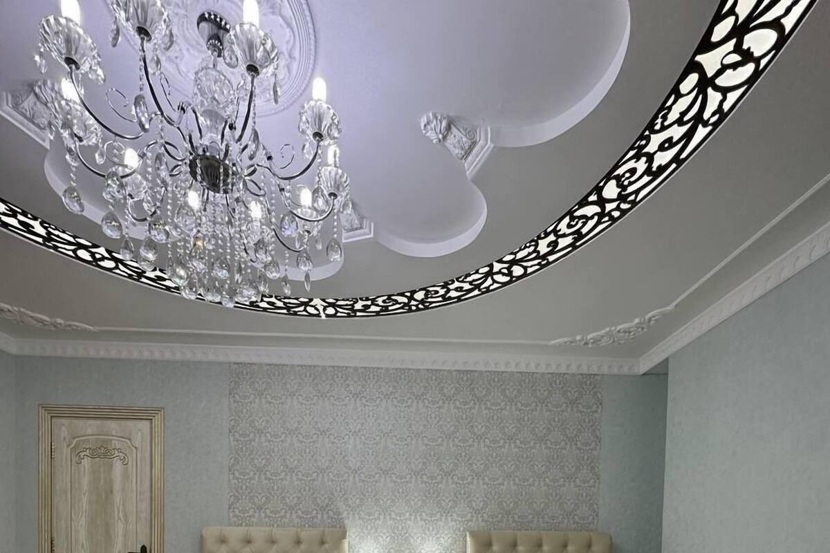 Une chambre avec deux lits, un lustre et un mur orné d’un motif.