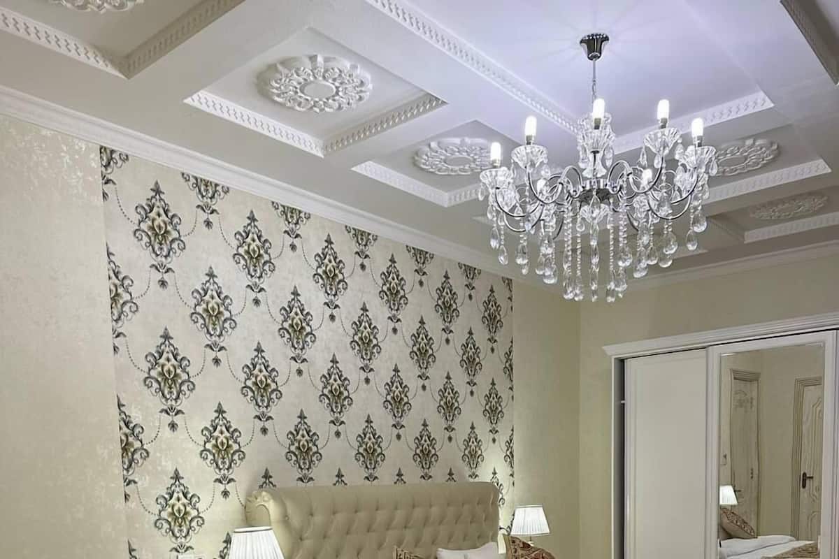 Une chambre à coucher avec un grand lit, une table de chevet, une table noire et un lustre.