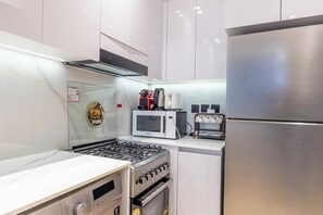 Eine kompakte Küche mit Gasherd, Mikrowelle, Toaster und Edelstahl-Kühlschrank.