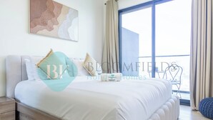 Une chambre avec un grand lit, une table de chevet, une chaise et une vue sur l’extérieur.