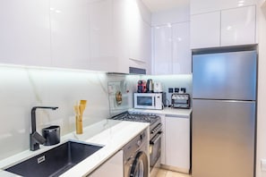 Une cuisine moderne équipée d’appareils électroménagers en acier inoxydable, d’un four encastré et d’un four à micro-ondes.