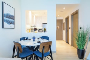 Un coin repas avec une table dressée pour deux personnes, des chaises et une plante en pot.