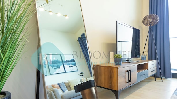 Un salon moderne avec un grand miroir, une console en bois, un lampadaire et une plante en pot.