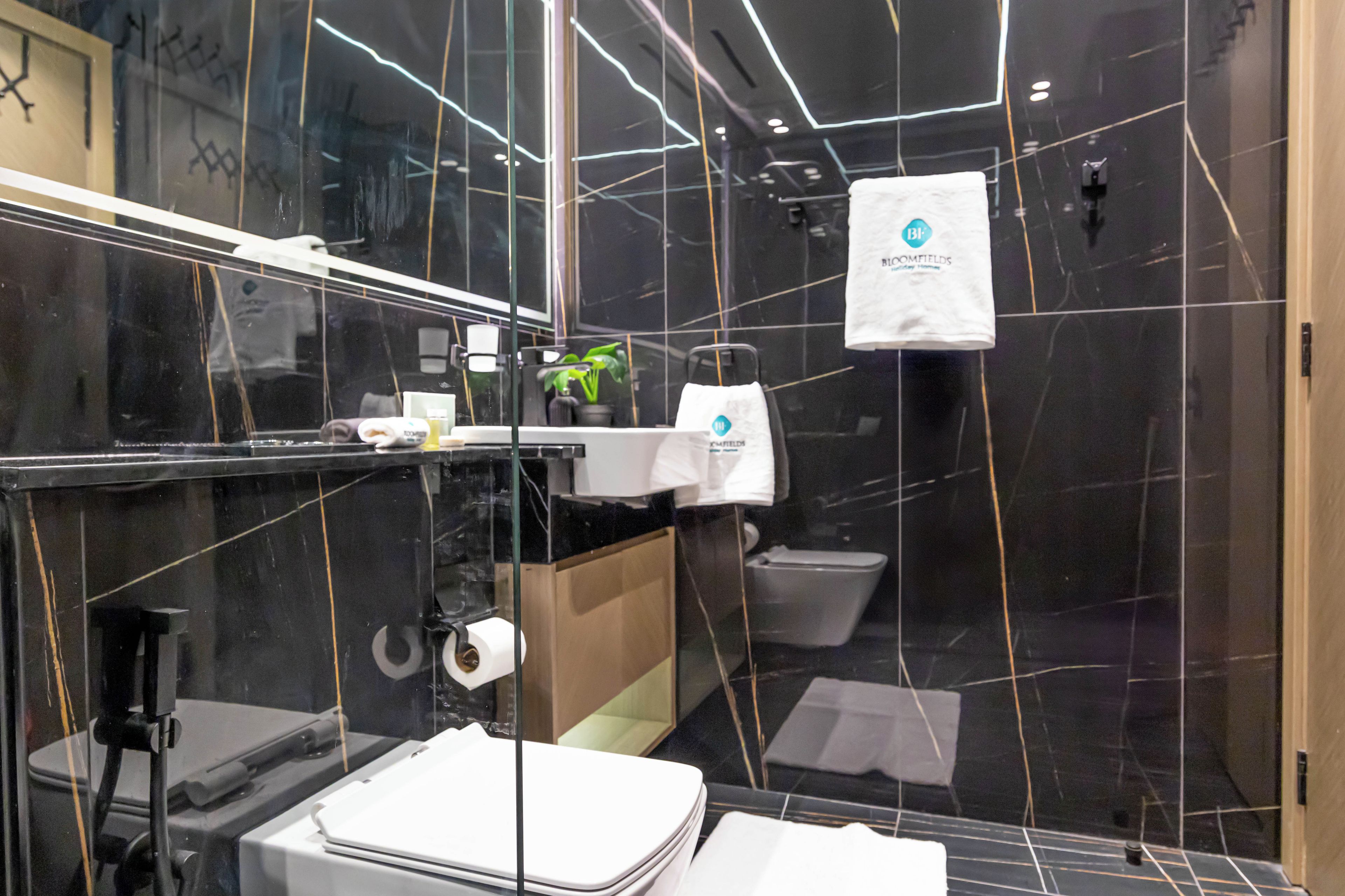A modern bathroom with a glass shower enclosure, a toilet, and a sink area with toiletries.