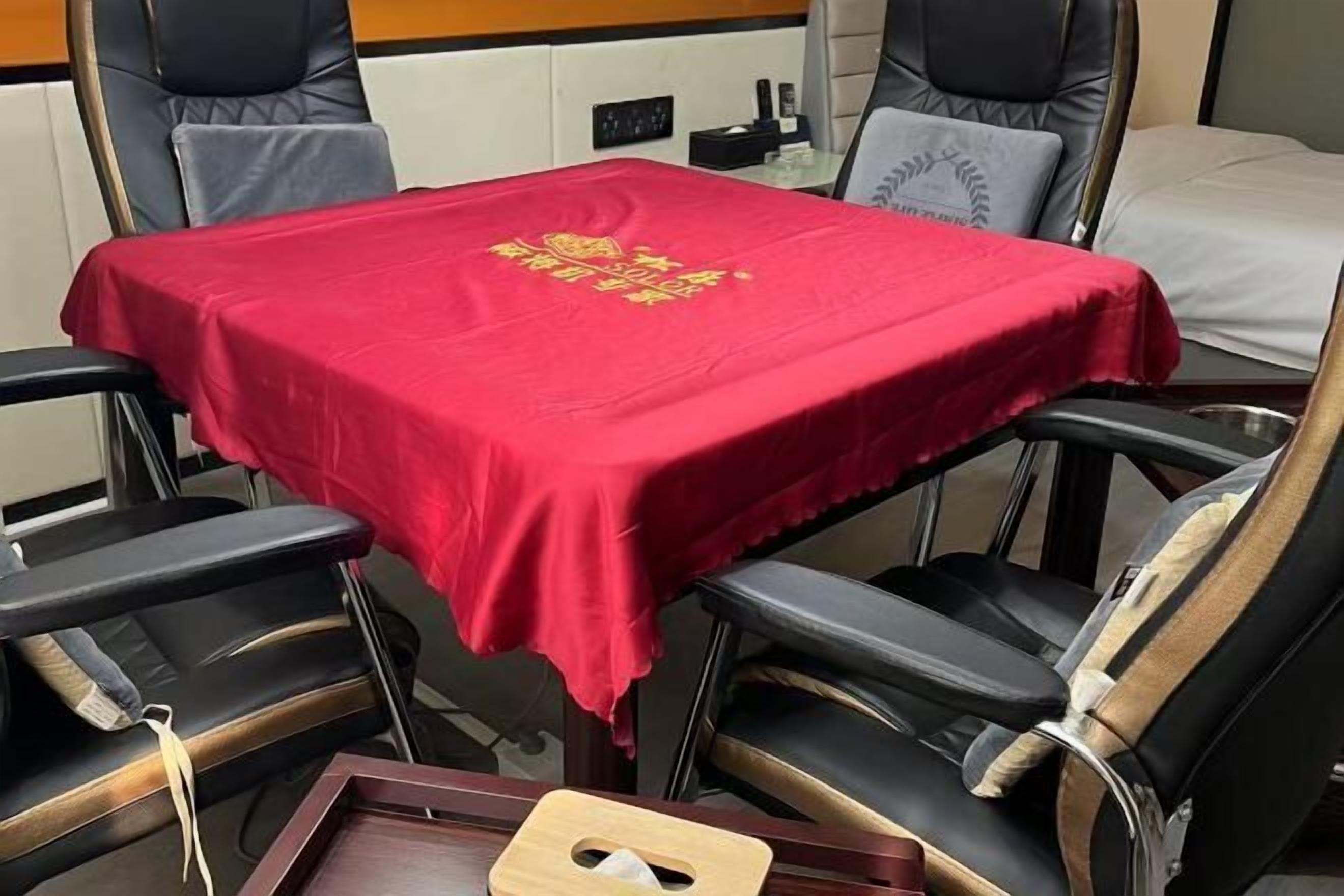 Habitació d'hotel amb estovall vermell, cadires de pell negra i safata de fusta.