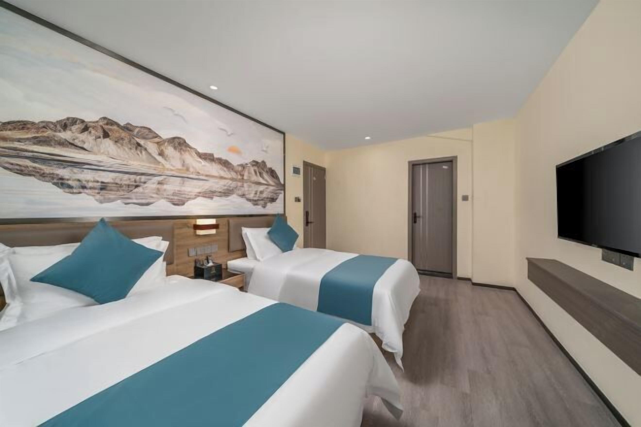 A hotel room with two beds, a painting on the wall, a flat-screen TV, and a wooden floor.