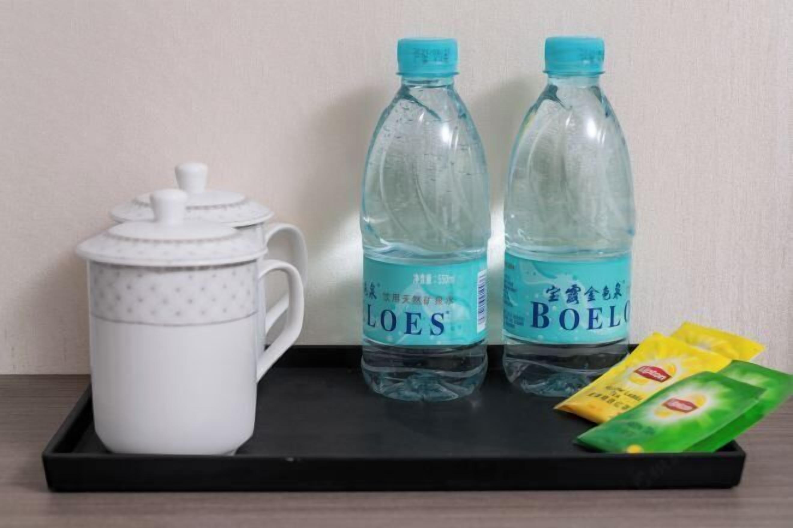 A tray with a white mug, two water bottles, and packets of snacks.