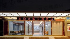 A hotel entrance with a glass facade, a reception desk, and a seating area visible through the glass. - Pomegranate Hotel (Guangzhou Baima Garment City Railway Station Subway Station Branch) (Guangzhou)