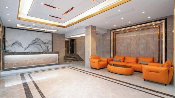 A modern lobby with a reception desk, orange seating area, and a marble reception wall. - Pomegranate Hotel (Guangzhou Baima Garment City Railway Station Subway Station Branch) (Guangzhou)