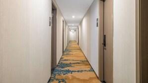 A hotel hallway with a carpeted floor, doors on both sides, and a sign indicating the direction to the elevator. - Pomegranate Hotel (Guangzhou Baima Garment City Railway Station Subway Station Branch) (Guangzhou)