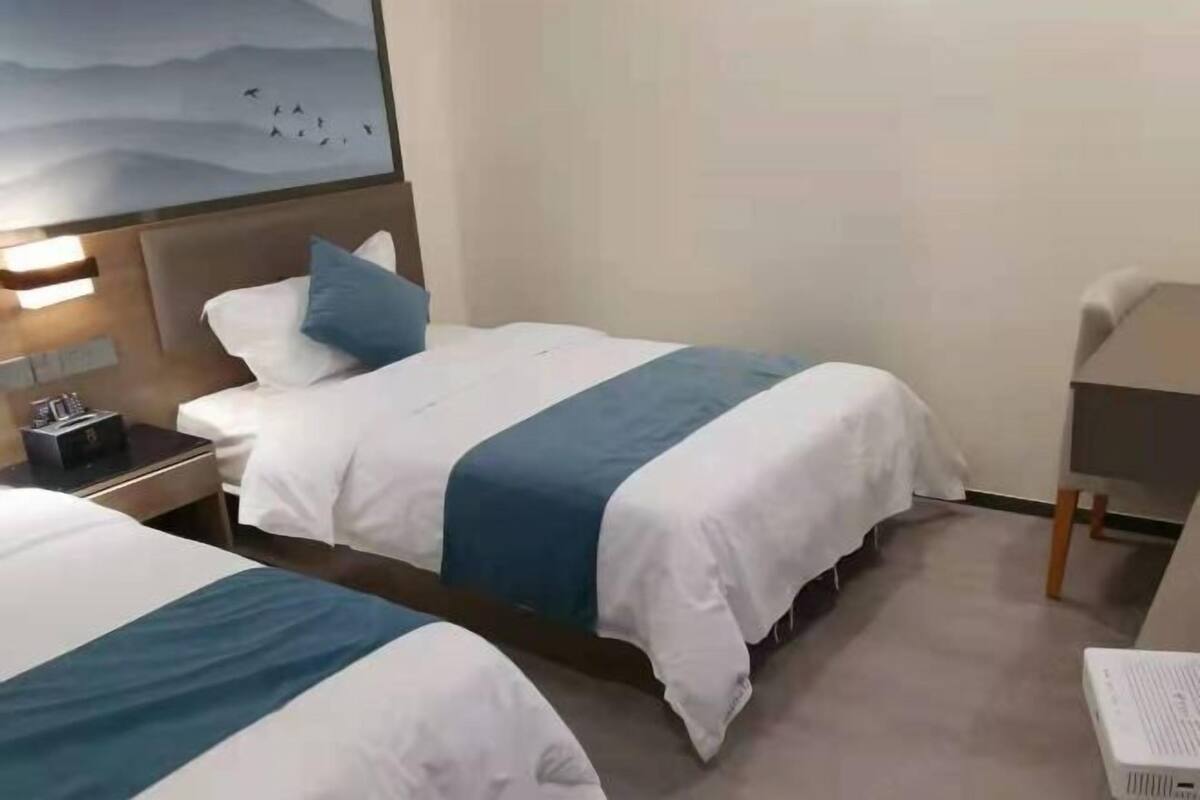 Una habitación de hotel con dos camas, un escritorio, una silla y un proyector.