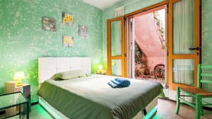 A bedroom with a bed, bedside lamps, a chair, and a view of the outside. - [Spacious +sea view with garden] (Arenzano)
