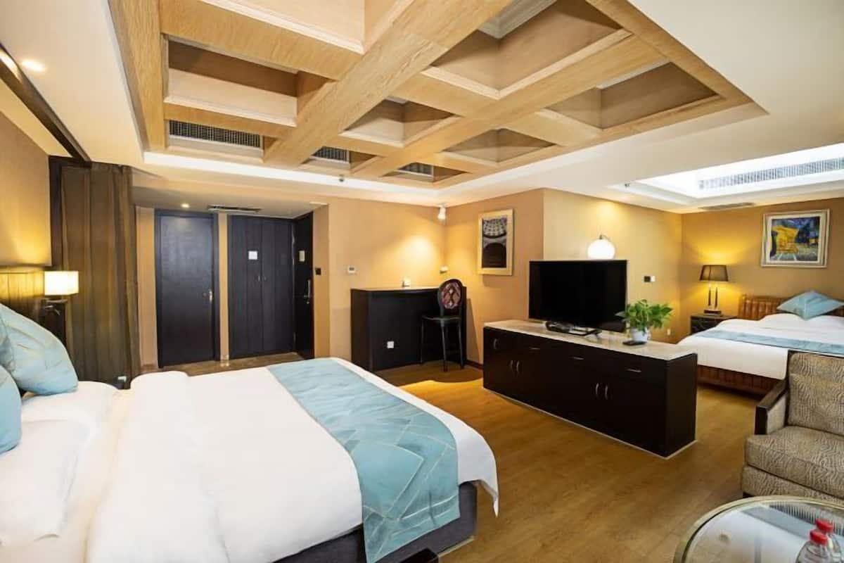 Une chambre d’hôtel avec un grand lit, un bureau, une télévision et un petit balcon.