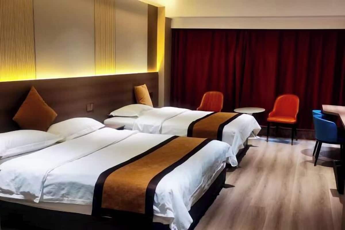 Une chambre d’hôtel avec deux lits, un rideau rouge et une petite table avec des chaises.