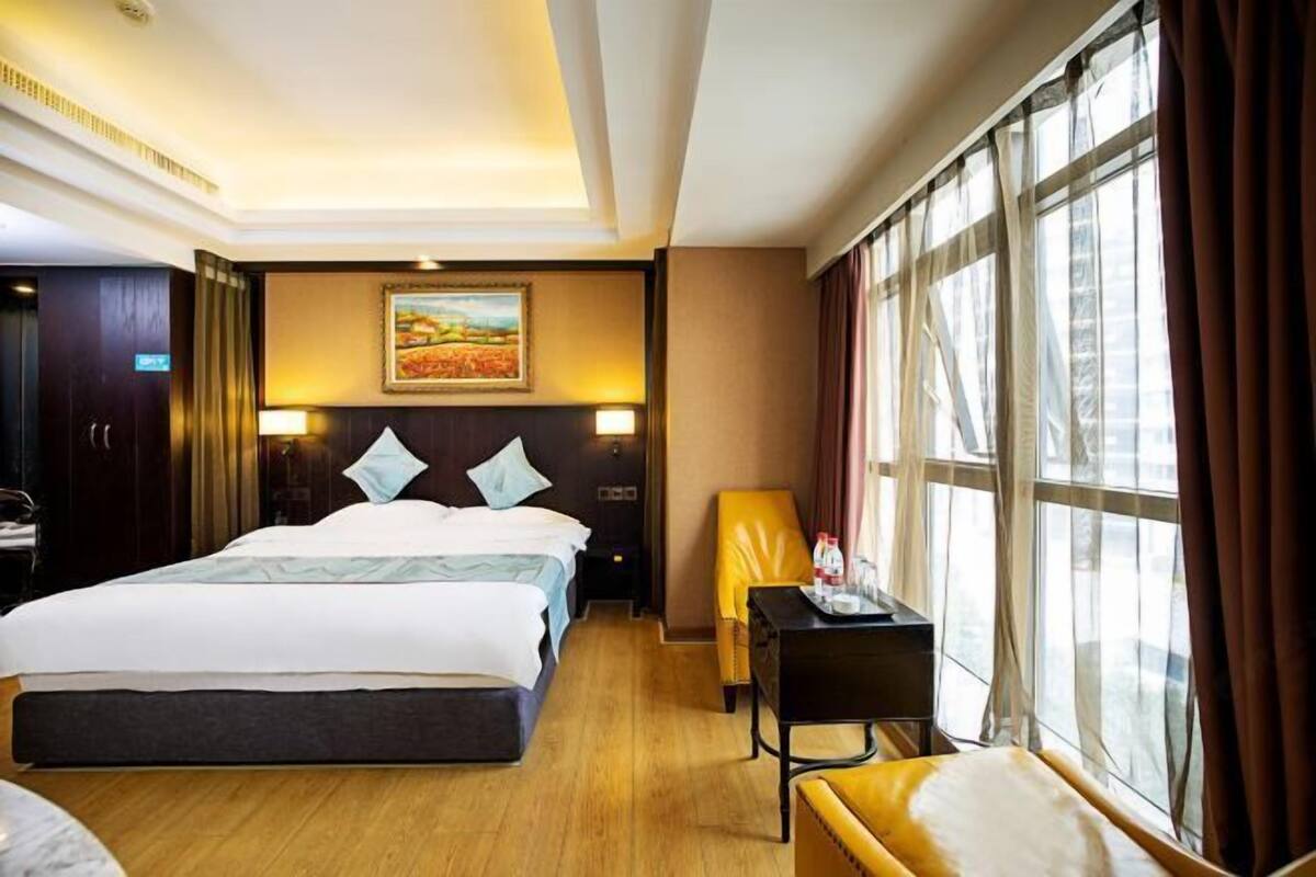 Une chambre d’hôtel avec un grand lit, un bureau, une chaise et une fenêtre avec des rideaux.