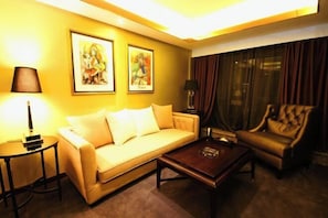 Habitación de hotel con sofá, sillón, mesa de centro y dos cuadros enmarcados en la pared.