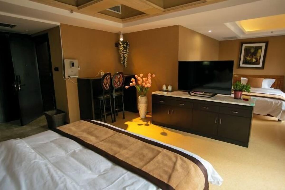 A hotel room with a bed, a TV, a desk, and a chair.