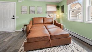 Una habitación con sofá seccional, una mesita auxiliar y un tapete estampado.