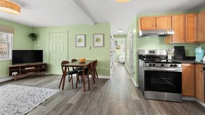 Una cocina moderna con armarios de madera, una estufa de acero inoxidable y un comedor con mesa y sillas.