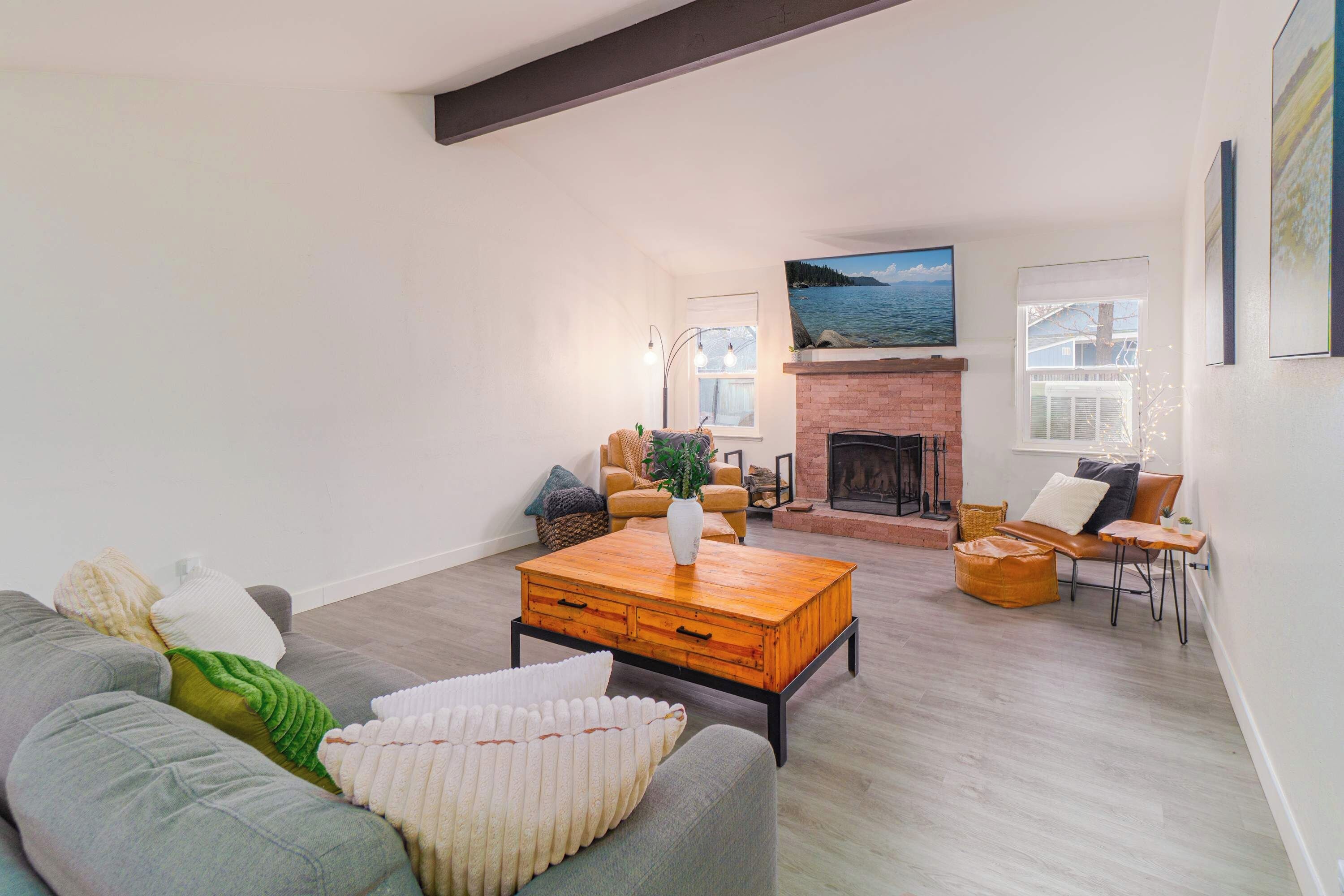 Un salón espacioso con chimenea, un ventanal con vistas al mar y una zona de estar acogedora con sofá y sillones.
