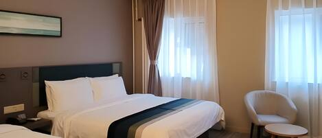 Une chambre d’hôtel avec deux lits, une chaise et un tableau au mur.