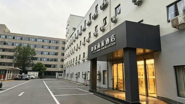 A hotel with a modern facade, a parking lot, and a clear sky. - Homeinn Selected Hotel (Beijing Shangdi Qinghe Subway Station) (Beijing)