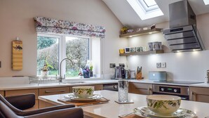 A modern kitchen with a skylight, a dining area with a table set for two, and a view of the outdoors. - 1 bedroom accommodation in Netherseal (Netherseal)