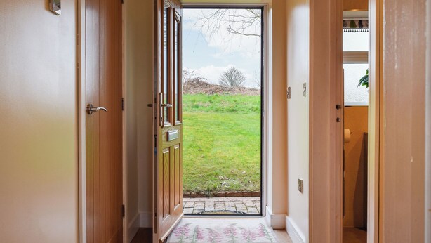 A hallway with a wooden door leading to a glass door opening to a grassy area. - 1 bedroom accommodation in Netherseal (Netherseal)