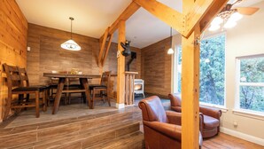 A wooden interior with a dining area, leather chair, and a fireplace.