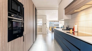 Een moderne keuken met inbouwapparatuur, een lange werkblad en uitzicht op de eetruimte.