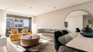 Een moderne woonkamer met een bank, fauteuils, een salontafel en een eettafel.