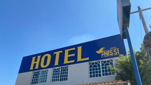 Une enseigne d’hôtel avec le nom « HOTEL NISSI » écrit en grandes lettres jaunes sur un fond bleu.