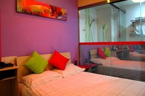 A hotel room with a bed, a nightstand, a mirror, and a painting on the wall.