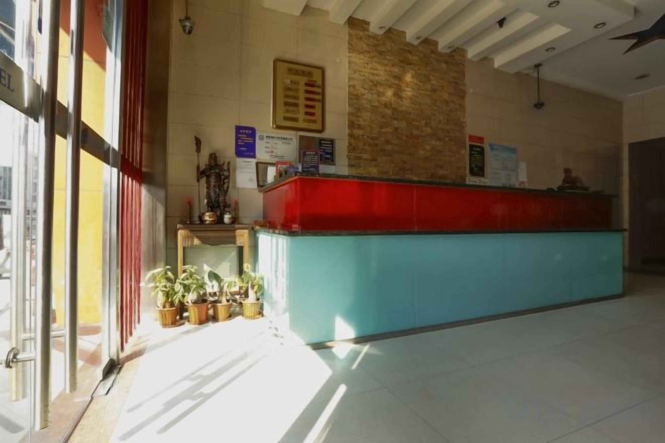 Un área de recepción con mostrador, plantas en macetas y un panel de menú en la pared.