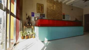 Un área de recepción con mostrador, plantas en macetas y un panel de menú en la pared.